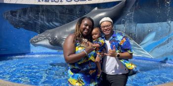 Craven CC alum Akiim Allen poses with his wife and small child wearing matching Hawaiian-patterned clothing in front of a Maui aquarium center