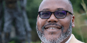 Man in suit jacket stands in front of statue