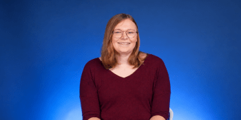 Woman wearing red shirt sits in front of blue background