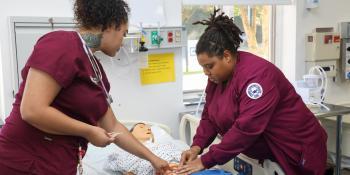 Two nursing students care for a simulated patient